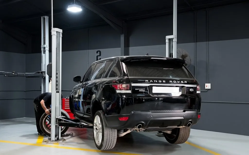 A black Range Rover Sport parked in a marked workshop bay in front of the lifts