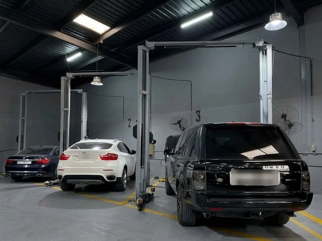 A black Range Rover and a white BMW X6 parked in the workshop bays under the two-post lifts